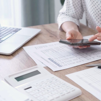 A woman using digital calculators for tax and finances.