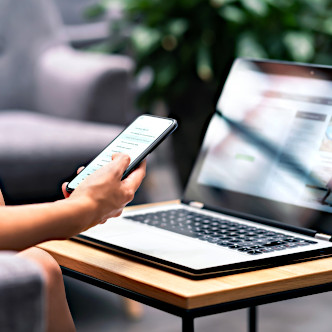 A person reading accounting newsletters on their phone and laptop.