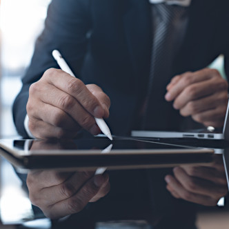 Person in suit signing a document digitally with a tablet.